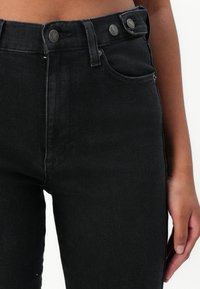 High-waisted black denim jeans with a smooth texture, two front pockets, and double-button closure at the waistband.