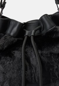 Borsa nera in faux fur con bordi in pelle nera liscia, dotata di chiusura a cordoncino e solide finiture in corda nera.