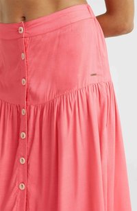 Jupe maxi rose en tissu léger avec un design froncé, fermeture à boutons sur le devant et un petit emblème de marque sur la taille.