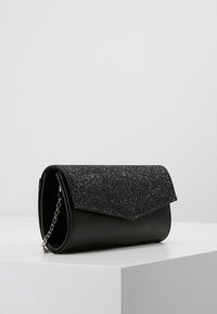 Sac à main noir avec un rabat pailletté noir, au design élégant et à bandoulière chaîne. Fabriqué en matériaux synthétiques avec une texture lisse.