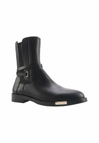 Bottines noires en cuir avec une texture lisse, bout arrondi et un accent de sangle avec une boucle en métal. Semelle en caoutchouc plate avec logo de la marque.