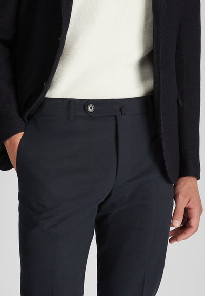 Pantaloni blu navy con vestibilità su misura, caratterizzati da un fronte piatto, passanti per cintura e chiusura con un unico bottone. Tessuto liscio con un leggero luccichio.