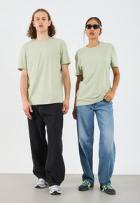Light green cotton t-shirts with short sleeves worn with dark jeans and light blue jeans. Sneakers complement the casual attire.