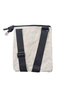 Sac blanc texturé avec des bretelles noires ajustables et une fermeture zippée. Présente une surface lisse et plissée avec du matériel noir contrastant.