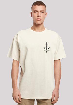 Beige cotton t-shirt with short sleeves, featuring a black graphic print of arrows and an anchor on the front. Classic crew neck design.