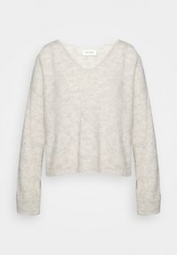 Pull cropped à col en V en gris clair, fabriqué en matériau tricot doux avec une finition texturée. Il possède des manches longues et des poignets côtelés.