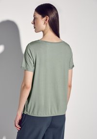 Koszulka z krótkim rękawem, jasnoniebieska, z okrągłym dekoltem, wykonana z miękkiego materiału i o lekko luźnym kroju. Prosty design bez widocznych wzorów czy akcentów.