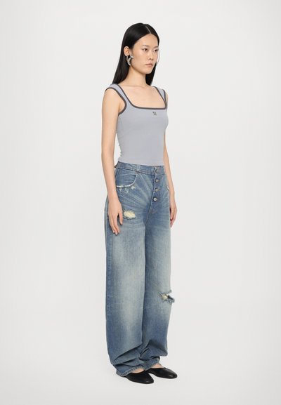Grå tætsiddende tanktop med kontrasterende mørke stropper, parret med lys blå slidte brede jeans og sorte slip-on sko.
