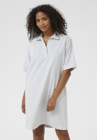 Robe chemise rayée en bleu clair et blanc. Présente un col classique et des manches courtes. Tissu doux avec une coupe décontractée et un ourlet légèrement arrondi.