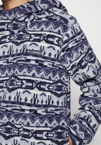 Felpa con cappuccio in navy e azzurro chiaro con motivi geometrici. Presenta un cappuccio e una toppa con il logo Columbia sulla parte anteriore. Texture morbida.