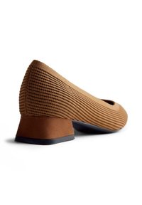 Pompe en textile marron avec un design côtelé, bout rond et petit talon carré. Le talon a une base noire, offrant de la stabilité.