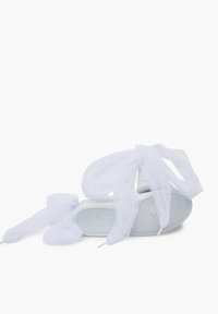 White sandal featuring a soft, flowing white fabric tied around the ankle, set against a plain background.