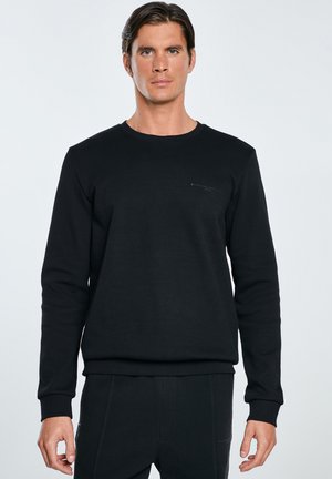 Sort crewneck sweatshirt lavet af blødt stof, med lange ærmer, ribbede manchetter og en subtil logo detalje på brystet.