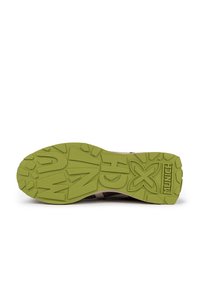 Semelle de chaussure avec un extérieur en caoutchouc vert, doté d'un motif de traction prononcé, d'une inscription en relief et d'accents beiges le long du bord.