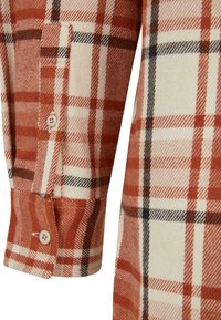 Plaid shirt featuring orange, cream, and black colors. Cotton fabric with a classic check pattern and button detailing on the cuff.