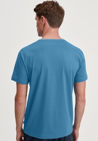Blauwe katoenen t-shirt met korte mouwen, een ronde hals en een gladde textuur, met een eenvoudige achterkant.