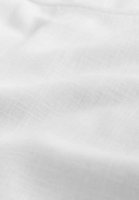 Hvid linnedstof med en blød tekstur og et subtilt ternet mønster, der viser naturlige fibre og et let, luftig udseende.