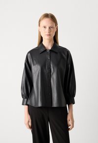 Zwarte leren shirt met een kraag, knoopsluiting aan de voorkant en opgeblazen lange mouwen. Gladde textuur en een losvallend ontwerp.