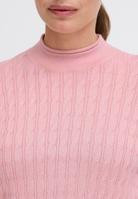 Maglione lavorato a maglia di un rosa chiaro con collo alto, caratterizzato da un motivo a treccia e una texture a coste per un tocco di dettaglio e calore.