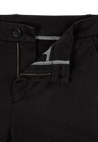 Pantalones negros con cierre de cremallera, botón y presillas para cinturón. Presentan un forro interior a rayas y una textura de algodón suave.