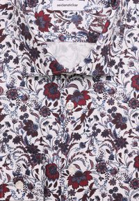 Chemise blanche boutonnée avec motif floral rouge et bleu et col, montrant l’étiquette de la marque Seidensticker à l’intérieur.