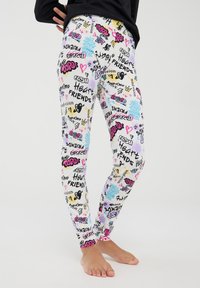 Leggings a fantasia con un design colorato che presenta testo grafico nero, rosa, giallo e blu, cuori e forme su uno sfondo bianco.