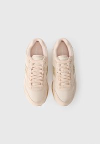 Helles pinke Sneakers aus Mesh- und Wildledermaterialien, mit strukturiertem Zehenkappen und goldenen Akzenten sowie einem auffälligen Schnürsystem.