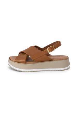 Sandale à plateforme en cuir marron avec des lanières croisées, une boucle dorée réglable et une semelle beige avec un bord blanc.