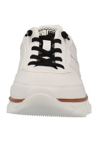 Chaussure de sport blanche avec une tige en cuir perforé, des lacets noirs et une semelle blanche texturée avec un accent brun.