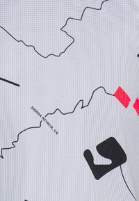 Del av en vit tygkarta som visar konturerna av Sierra Nevada i Kalifornien med svarta och röda geometriska former samt ett rutmönster.