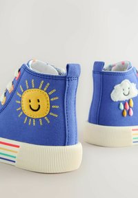 Blaue Canvas-Hochschaftschuhe mit einer gelben Sonne und einer weißen Wolke, die an den Seiten gestickt sind; Gummisohlen mit einem mehrfarbigen Streifen-Detail.