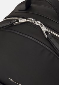 Zaino in nylon nero con zip silver, una texture liscia e un logo sul davanti. Dotato di spallacci regolabili.