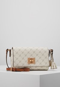 Cream-colored crossbody bag with textured finish, gold hardware, and a decorative tassel. Features a patterned design and adjustable strap.
