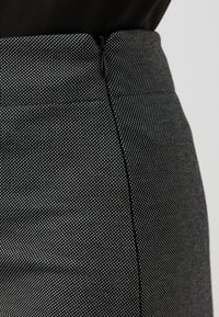 Gonna a pois neri e bianchi con tessuto testurizzato, vita alta e chiusura con zip nascosta sul lato.
