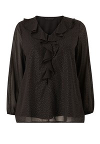 Zwarte blouse met lange mouwen, gerimpelde halslijn en kleine witte stippen. Gemaakt van een lichtgewicht, doorschijnende stof.