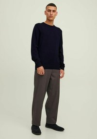 Maglione blu navy con maniche lunghe, abbinato a pantaloni grigi e scarpe nere. Design semplice con scollatura tonda e polsini a coste.