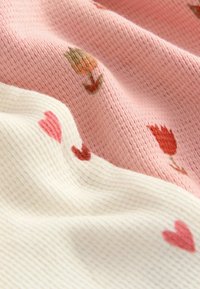 Strikstof med skiftende teksturerede striber i blød rosa og hvid, prydet med broderede blomster og hjerte mønstre i varme farver.