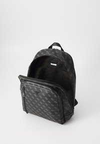 Zaino nero con un design a motivo. Presenta una tasca anteriore con zip e un vano principale aperto. Il materiale sembra resistente e con una texture particolare.