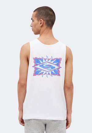 Homme portant un débardeur blanc avec un graphisme en forme de soleil bleu et rose et un "S" stylisé dans le dos, tourné vers la gauche sur un fond uni.