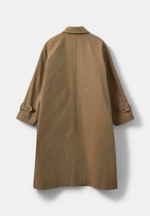 Cămașă bej cu un guler la gât, cu mâneci raglan și manșete cu nasturi. Prezintă o textură netedă și un design de lungime medie.