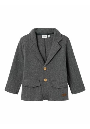 Blazer pour enfant gris à motif chevrons, avec deux boutons marron, larges revers et poches à rabat sur les côtés avant.