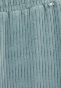 Gaiši zils ribotais audums ar mīkstu tekstūru un elastīgu jostu; sānos ir neliels zvaigznes logotipa birkas.