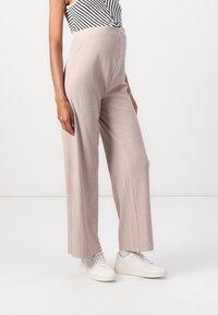 Helle beige Weitbein-Hosen mit vertikal gerippter Textur und hohem Bund, kombiniert mit weißen Sneakers für einen lässigen Look.