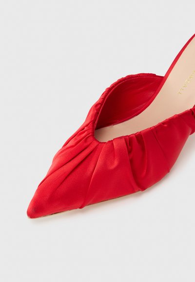 Κόκκινο γοβάκι με μυτερή μυτούλα από σατέν, με ρυτιδωτή υφή γύρω από το άνοιγμα, διαθέτει ομαλή εσωτερική επένδυση και διακριτικό χρυσό λογότυπο.