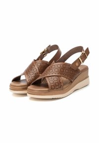 Sandalias de cuero marrón con diseño de flores cortadas a láser, correa ajustable en el tobillo y suela de cuña. Presenta una suela exterior de color beige claro para mayor agarre.