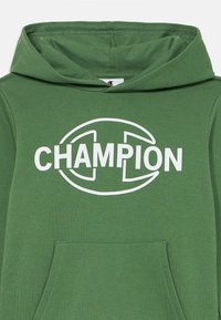 Grønn hettegenser laget av myk stoff med en front lomme, med en stor hvit "CHAMPION" logo sentrert på brystet.