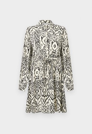 Pitkähihainen mustavalkokuvioitu paitamekko, jossa on kaulus ja vyötärölle solmittava vyö.