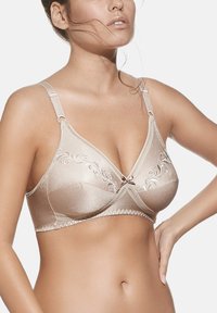 Sujetador beige con una textura de satén suave, bordado floral, tirantes ajustables y un lazo decorativo en el centro.