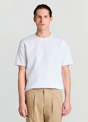 Weißes T-Shirt mit kurzen Ärmeln und geripptem Muster, Rundhalsausschnitt, kombiniert mit beigen, plissierten Hosen. Einfaches, modernes Design.