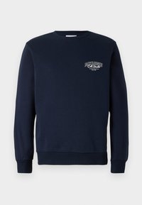 Marineblå genser laget av bomull, med rund hals, lange ermer, ribbestrikkede mansjetter, og en logo på brystet i hvit tekst.